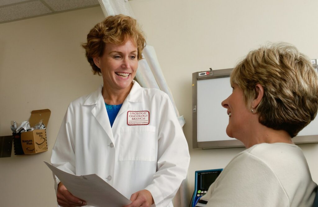 Un médecin souriant en blouse blanche parlant à un patient dans une clinique