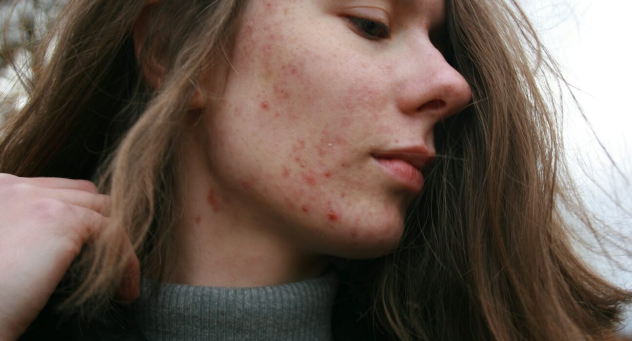 Une femme aux longs cheveux bruns portant un pull à col roulé gris