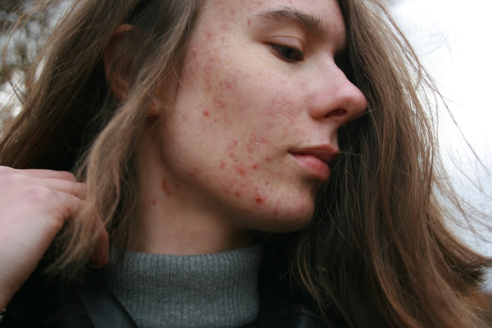 Une femme aux longs cheveux bruns portant un pull à col roulé gris