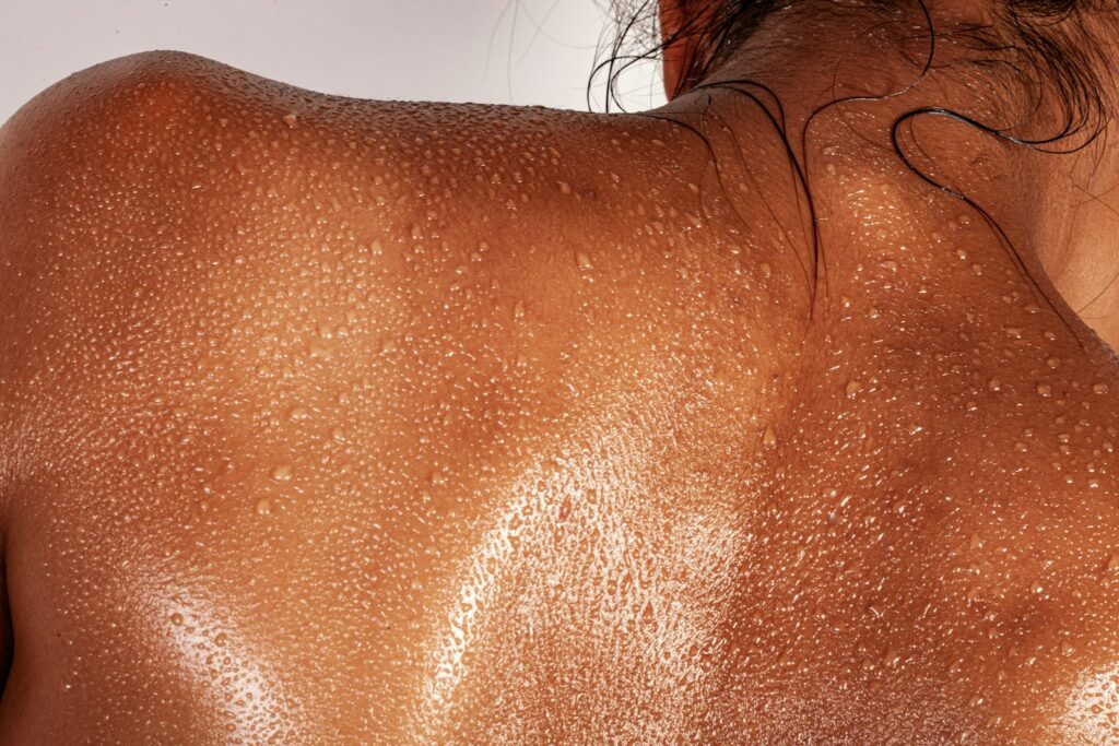 Le dos d’une personne couvert de gouttes de sueur avec des poils sombres au cou