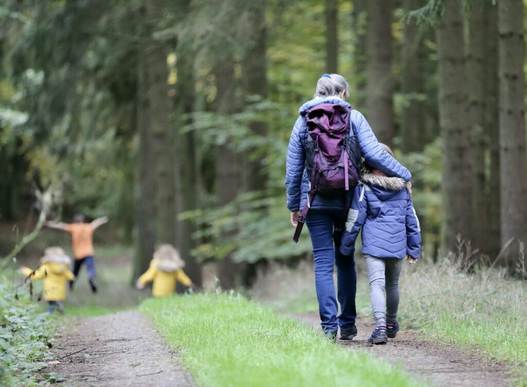 Un adulte et un enfant marchant sur un sentier forestier avec deux enfants devant