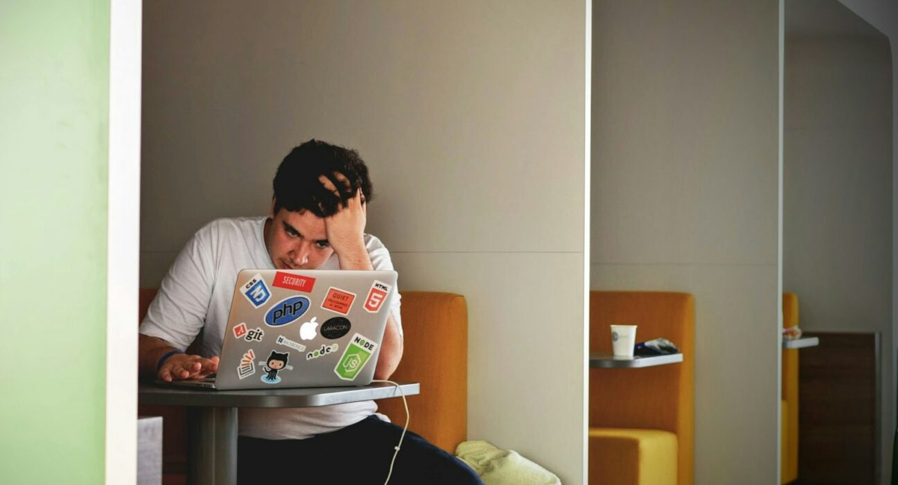 homme portant un haut blanc à l’aide d’un MacBook
