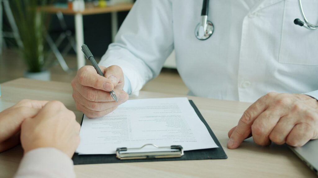Médecin écrivant sur le dossier d’un patient