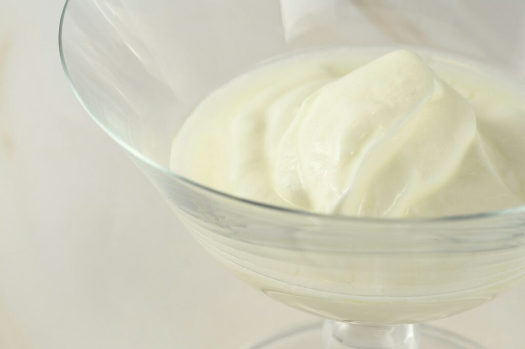 un bol en verre rempli de crème sur une table