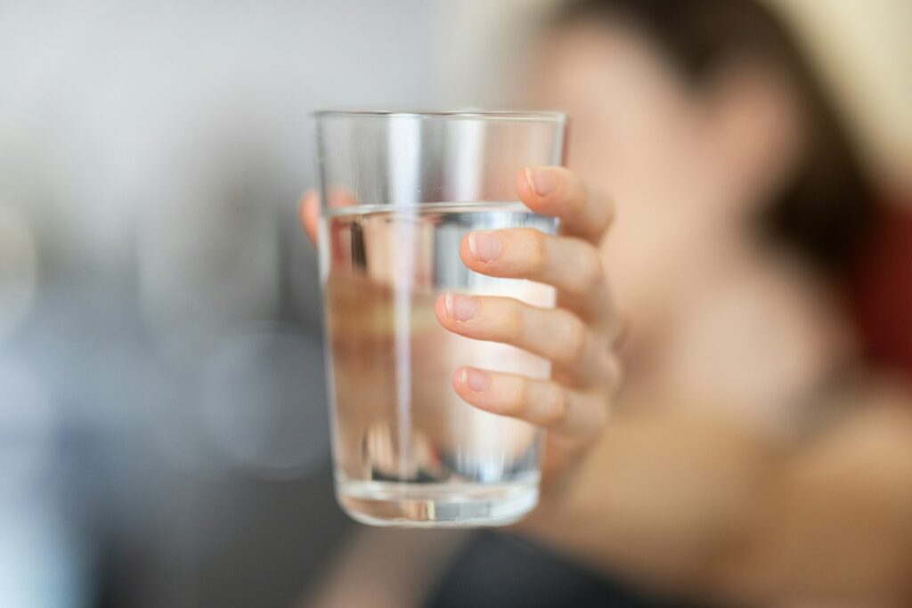 personne tenant un verre à boire transparent