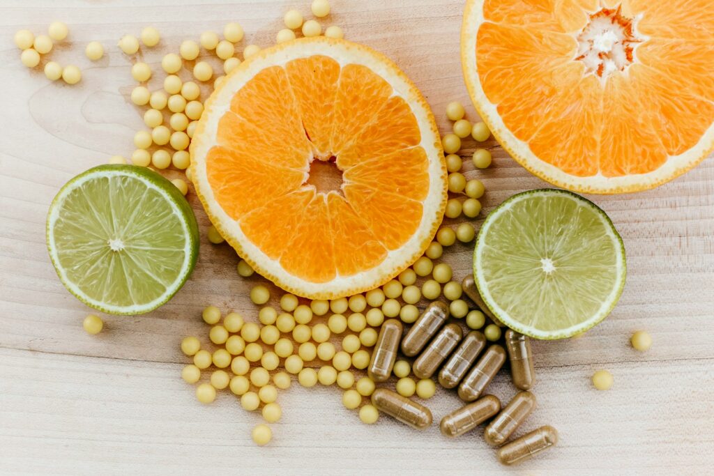 Tranches d’agrumes, petites perles jaunes de suppléments et capsules brunes sur une surface en bois