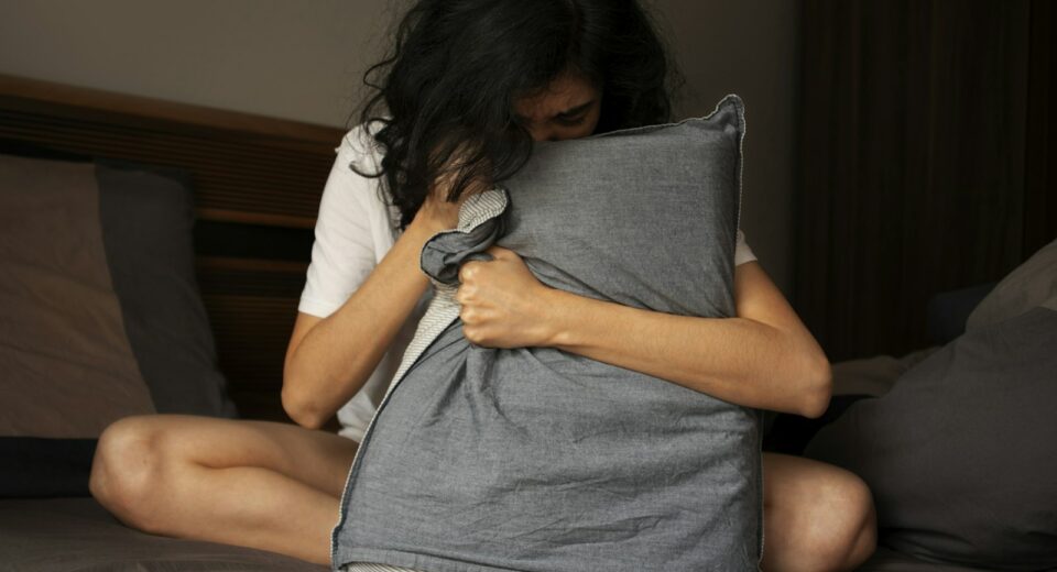 Une femme assise sur un lit tenant un oreiller