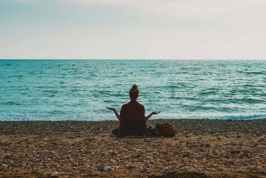 personne faisant du yoga au bord de la mer pendant la journée